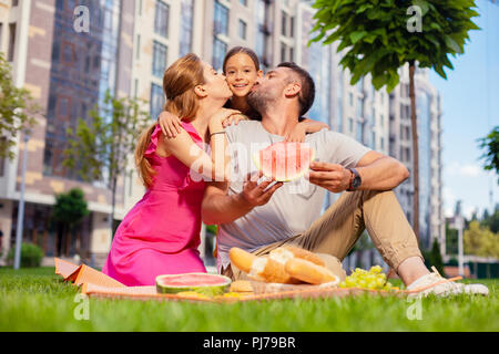 Delighted nice girl standing in between her parents Stock Photo