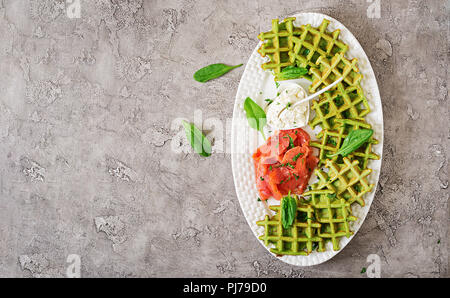 Savory waffles with spinach and cream cheese, salmon in white plate. Tasty food. Top view. Flat lay Stock Photo