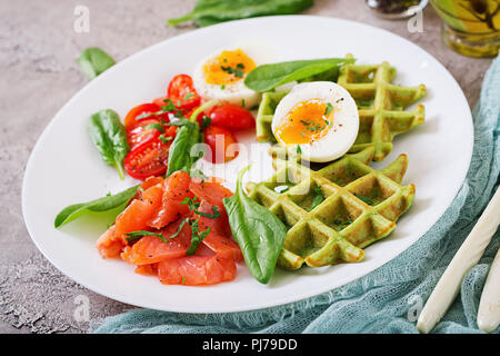 Savory waffles with spinach and egg, tomato, salmon in white plate. Tasty food. Stock Photo