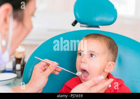 Pediatric dentist examining a little boys teeth in the dentists chair at the dental clinic. Dentist examining little boy's teeth in clinic Stock Photo