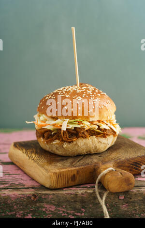 Pulled pork burger with homemade burger bun, pulled pork and coleslaw on wooden board Stock Photo