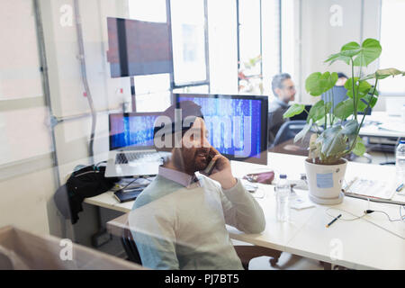 Indian computer programmer in turban talking on smart phone in office Stock Photo