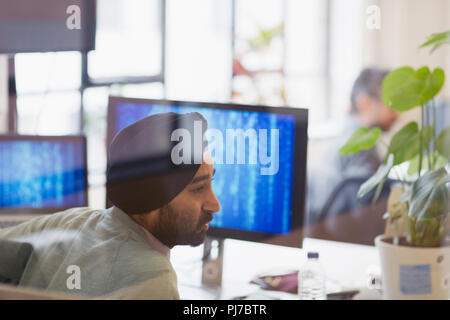 Indian computer programmer in turban working in office Stock Photo