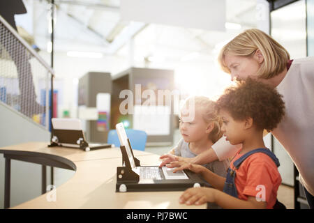 Teacher and schoolgirls using laptop in science center Stock Photo