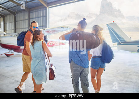 Friends with bags walking in airplane hangar Stock Photo