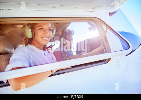 Smiling woman riding in small airplane Stock Photo
