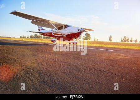 Prop airplane landing on sunny tarmac Stock Photo