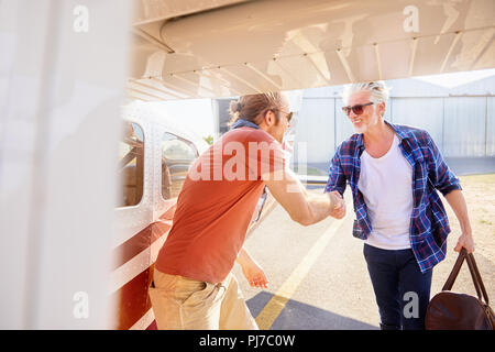 Pilot shaking hands with man boarding small airplane Stock Photo