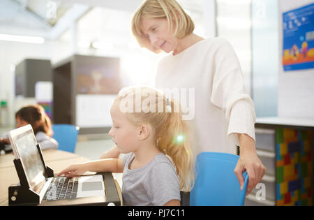 Teacher and schoolgirl using laptop in science center Stock Photo