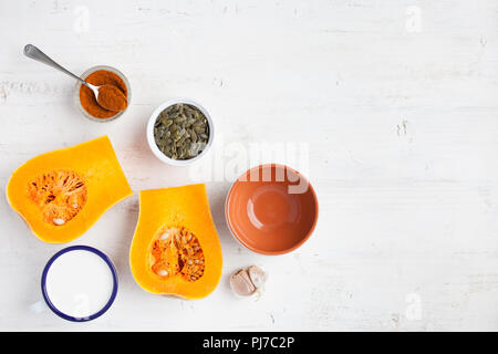 Spicy butternut squash soup ingredients on the white wooden table with copy space for text, top view Stock Photo
