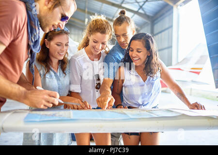 Friends planning trip at map in airplane hangar Stock Photo