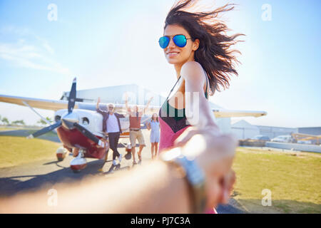 Personal perspective woman leading man by the hand toward prop airplane Stock Photo