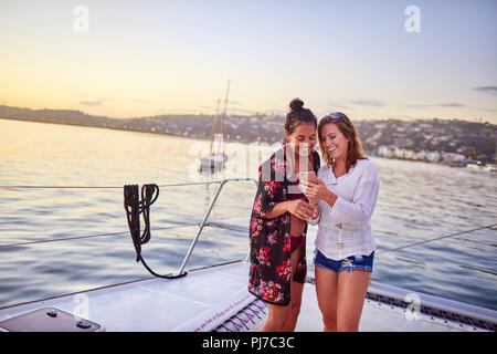 Young women using smart phone on catamaran Stock Photo