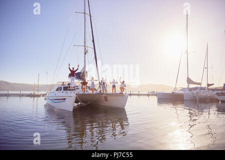 Portrait friends waving on catamaran in sunny harbor Stock Photo
