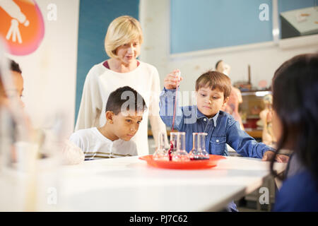 Teacher and students using pipette and beakers at interactive exhibit in science center Stock Photo