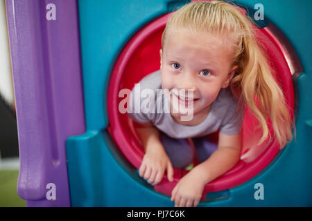 Portrait cute, happy girl playing in tube slide Stock Photo
