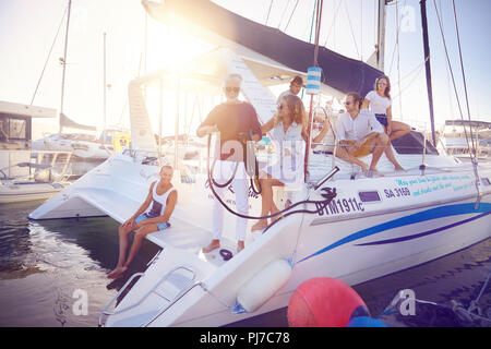 Friends relaxing on catamaran ins sunny harbor Stock Photo