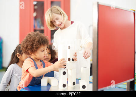 Teacher and curious students stacking large dominos in science center Stock Photo