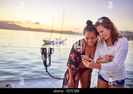 Young women friends using smart phone on boat Stock Photo
