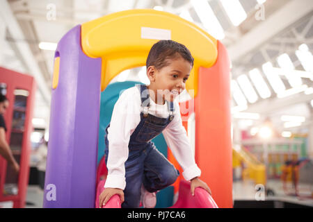 Smiling boy playing on slide Stock Photo