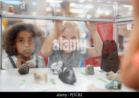 Silly girl making a face at rock exhibit display case in science center Stock Photo
