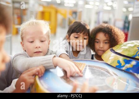 Curious kids at interactive globe exhibit in science center Stock Photo