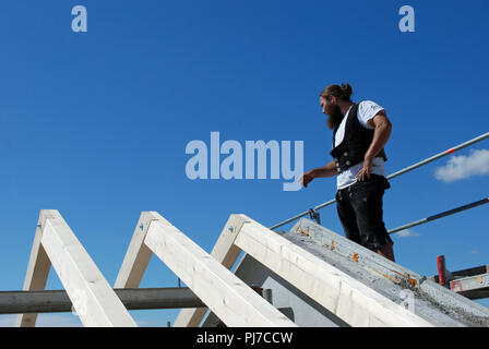 Carpenter in traditional work costume on roof of new house. Stock Photo