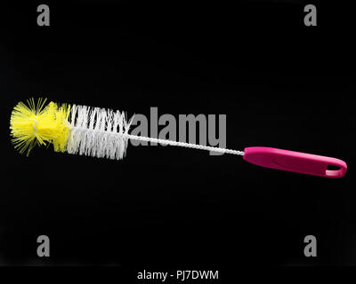 white and yellow bottle brush with pink handle isolated on black background. Stock Photo