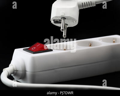 close up of power button and plug from a white power strip on black background. Stock Photo