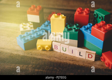 toy plastic brick with alphabet tiles word BUILD on wooden table. concept of children activity and growth Stock Photo