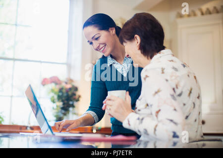 Daughter and senior mother using laptop in kitchen Stock Photo