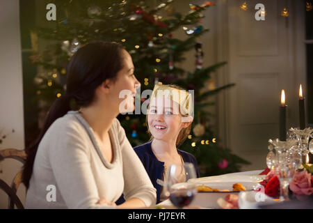 Happy mother and daughter in paper crown at candlelight Christmas dinner table Stock Photo