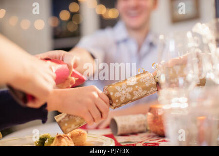 Family pulling Christmas crackers at dinner table Stock Photo