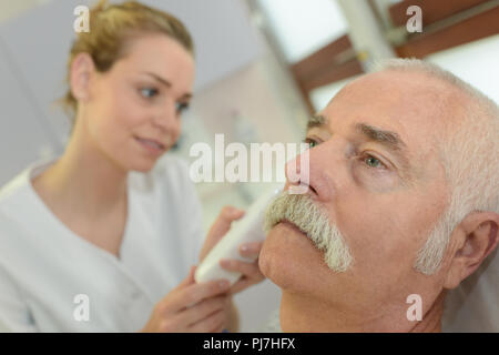 female doctor using an otoscope with senior patient Stock Photo