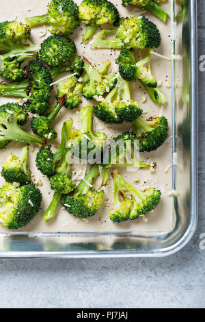 Roasted broccoli florets with cheese on a baking tray Stock Photo