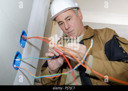 electrician installs paired socket on the wall Stock Photo