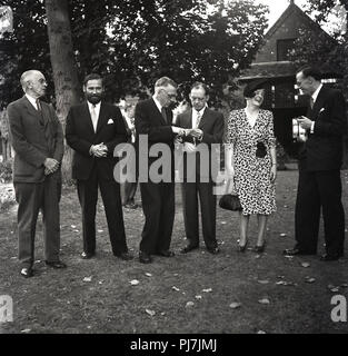 1950s, historical, group of well-dressed gentlemen and a lady standing together at a garden party or function, England, UK. Stock Photo