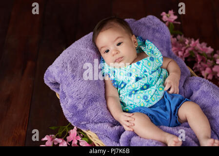 Portrait of cute baby girl on dark wooden studio background with copy space Stock Photo