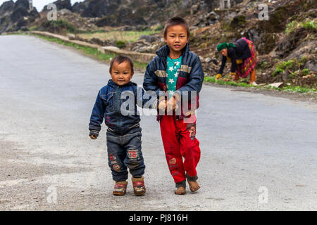 Ha Giang, Vietnam - March 18, 2018: Hmong ethnic minority children walking on a road in a remote rural area of the mountains of northern Vietnam Stock Photo