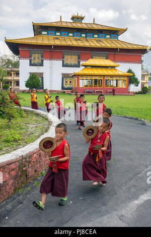 Gangtok, India - May 3, 2017: Unidentified young novice buddhist monks in traditional red robes practicing in playing Tibetan music instrument tingsha Stock Photo