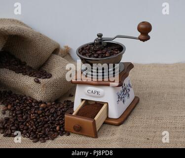 Freshly ground beans coffee in the traditional way in an old coffee grinder