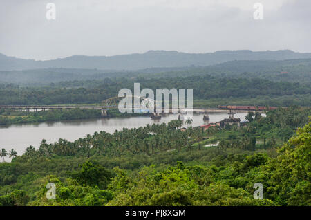 A freight train heading towards Divar Island going over the bridge on Mandovi River as seen from Church of Our Lady of the Mount, Old Goa, Goa, India. Stock Photo