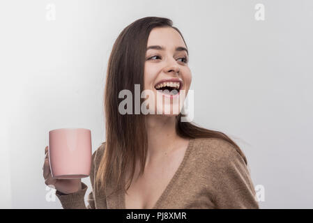 Beaming appealing woman holding pink cup with hot delicious tea Stock Photo