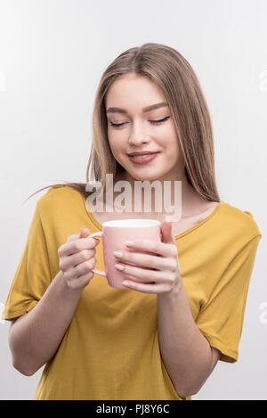 Appealing woman with long blonde hair holding cup with tasty tea Stock Photo