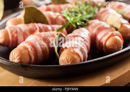 Pigs in blankets. Raw mini sausages wrapped in smoked bacon ready to baked