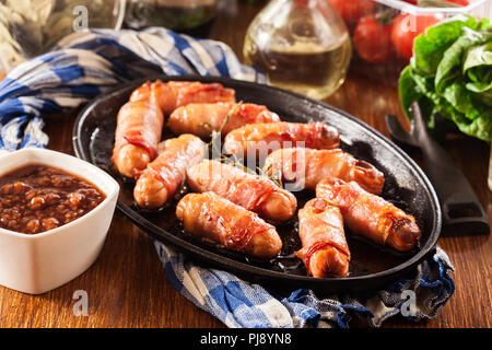 Pigs in blankets. Mini sausages wrapped in smoked bacon in baking dish Stock Photo