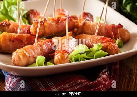 Pigs in blankets. Mini sausages wrapped in smoked bacon on a plate Stock Photo