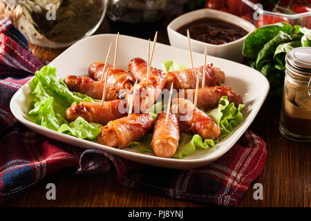 Pigs in blankets. Mini sausages wrapped in smoked bacon on a plate