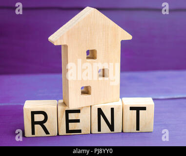 Wooden house on a purple background with the inscription rent. Rental of property, apartments. services of a realtor. affordable housing, rental price Stock Photo