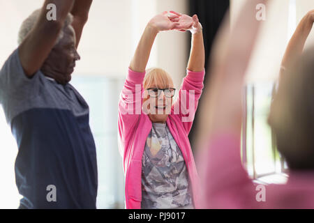 Smiling active seniors exercising, stretching arms Stock Photo